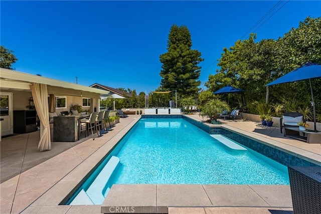 pool featuring a patio area and outdoor dry bar