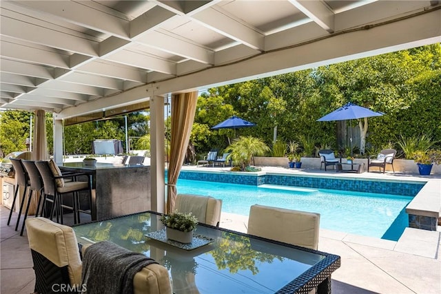 outdoor pool with outdoor dry bar, outdoor dining area, and a patio area