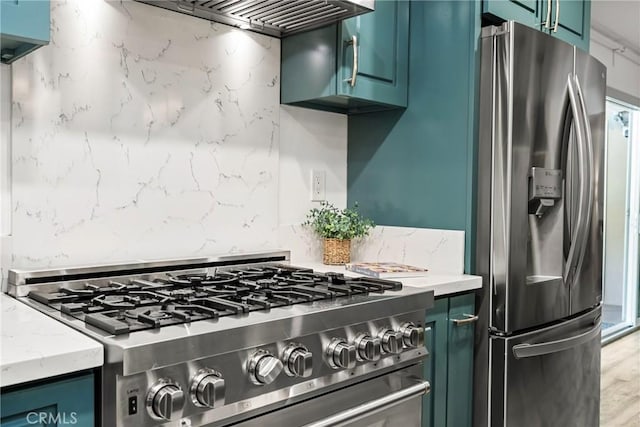 kitchen featuring wall chimney exhaust hood, light stone countertops, and appliances with stainless steel finishes