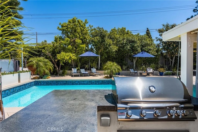 outdoor pool featuring a patio, a fenced backyard, and grilling area