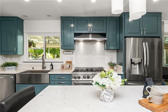 kitchen with light stone counters, decorative backsplash, under cabinet range hood, appliances with stainless steel finishes, and a sink