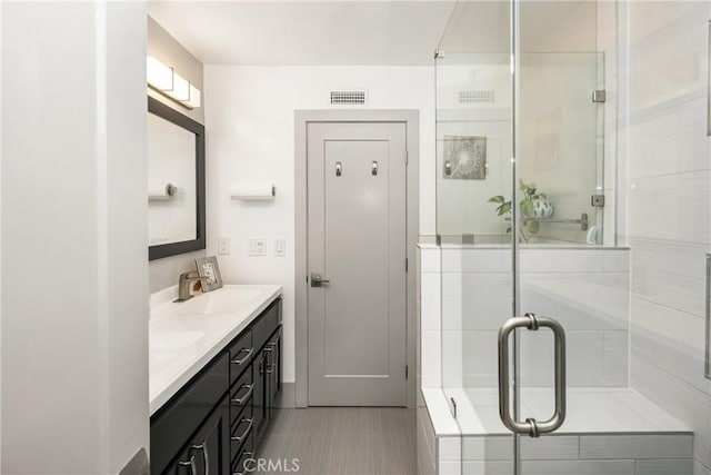full bath featuring double vanity, a sink, a shower stall, and visible vents