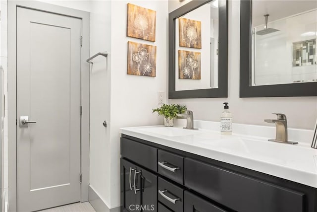 bathroom featuring walk in shower, double vanity, and a sink