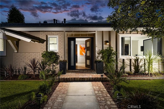 exterior entry at dusk featuring brick siding