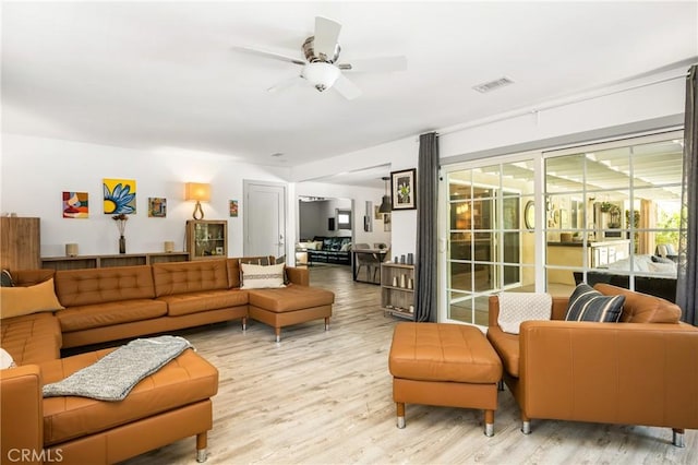 living room featuring ceiling fan, light wood-type flooring, and visible vents