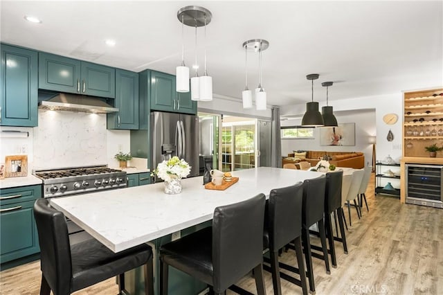 kitchen with beverage cooler, a breakfast bar, under cabinet range hood, stainless steel fridge with ice dispenser, and hanging light fixtures