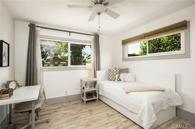 bedroom with ceiling fan, light wood-type flooring, and multiple windows