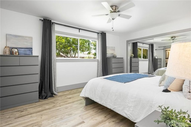 bedroom with ceiling fan, a closet, light wood finished floors, and multiple windows