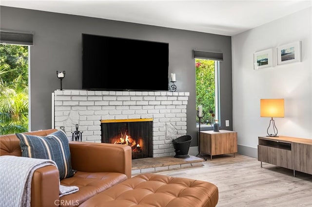 living area featuring light wood-type flooring, a healthy amount of sunlight, and a fireplace