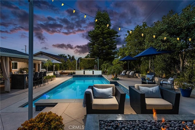 outdoor pool with a patio and an outdoor living space with a fire pit