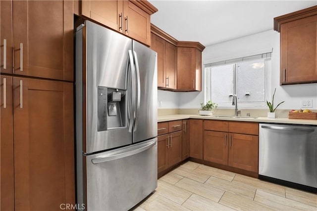 kitchen with light countertops, a sink, brown cabinets, and stainless steel appliances