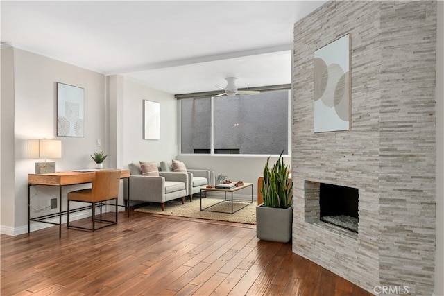 living room with baseboards, a ceiling fan, wood finished floors, and a fireplace