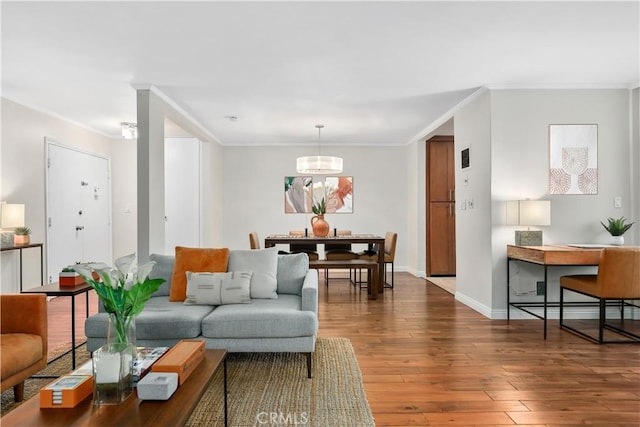 living area with baseboards, ornamental molding, hardwood / wood-style flooring, and a chandelier