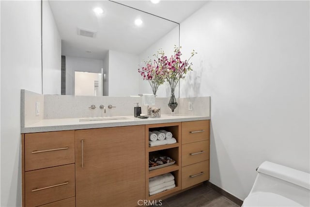 bathroom featuring toilet, visible vents, wood finished floors, and vanity