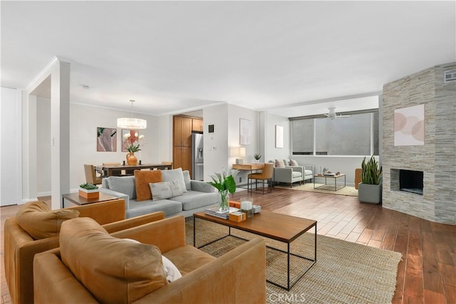 living room featuring wood-type flooring, a ceiling fan, and a fireplace