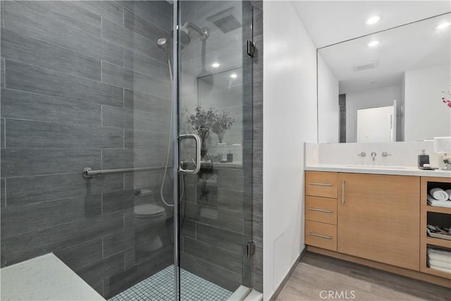 full bathroom with vanity, visible vents, wood finished floors, and a stall shower