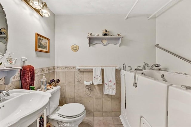 bathroom featuring a sink, tile patterned flooring, a bathing tub, toilet, and tile walls
