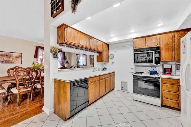 kitchen with brown cabinetry, light countertops, black appliances, and recessed lighting