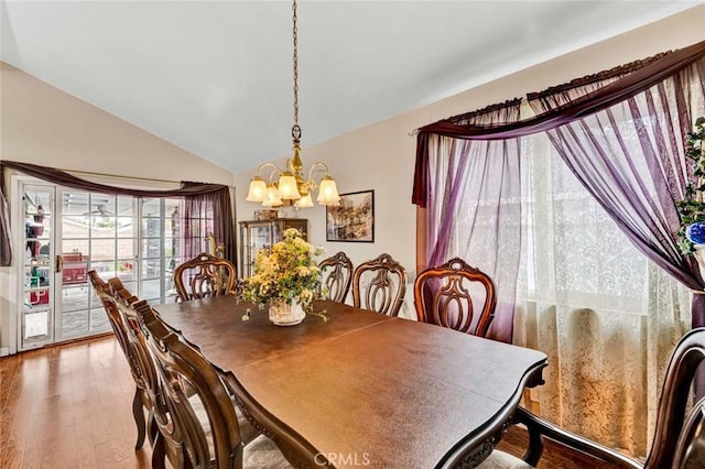 dining space featuring a chandelier, wood finished floors, and vaulted ceiling
