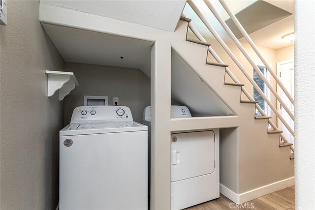 laundry area with baseboards, laundry area, washer and clothes dryer, and wood finished floors