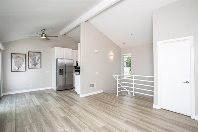 unfurnished living room with a ceiling fan, visible vents, baseboards, light wood finished floors, and vaulted ceiling with beams