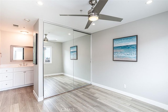unfurnished bedroom featuring visible vents, a sink, a closet, light wood finished floors, and recessed lighting