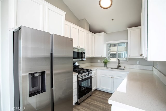 kitchen featuring a sink, appliances with stainless steel finishes, lofted ceiling, and white cabinets