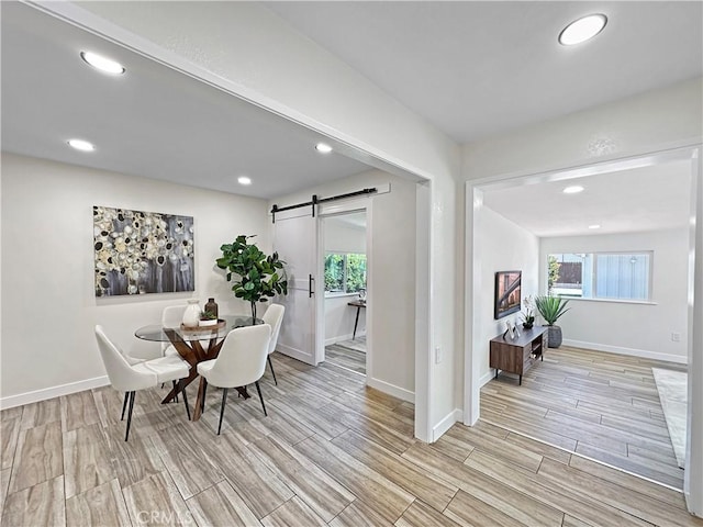 dining space with baseboards, a barn door, light wood-style flooring, and recessed lighting