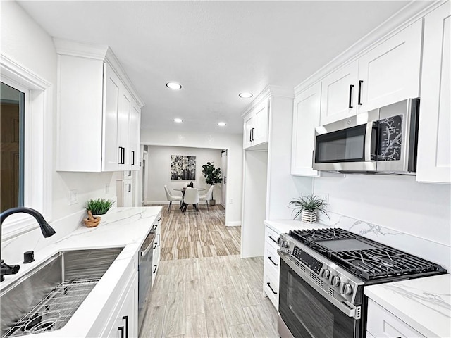 kitchen featuring recessed lighting, a sink, white cabinets, and stainless steel appliances