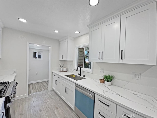kitchen with stainless steel range with gas stovetop, a sink, dishwashing machine, recessed lighting, and white cabinetry