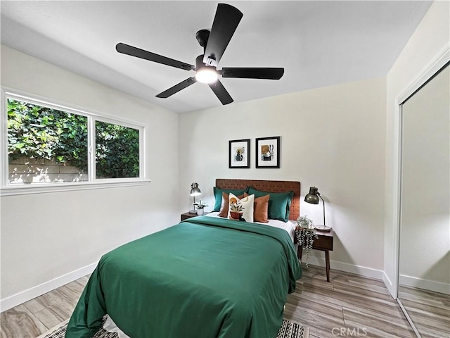 bedroom featuring a ceiling fan, baseboards, and wood finished floors
