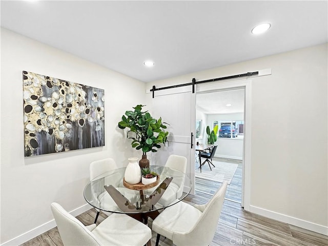 dining area featuring baseboards, a barn door, wood finished floors, and recessed lighting