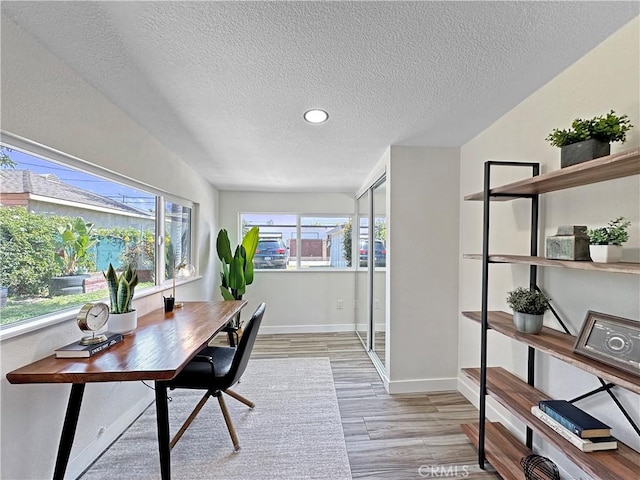 office space with recessed lighting, a textured ceiling, baseboards, and light wood-style floors