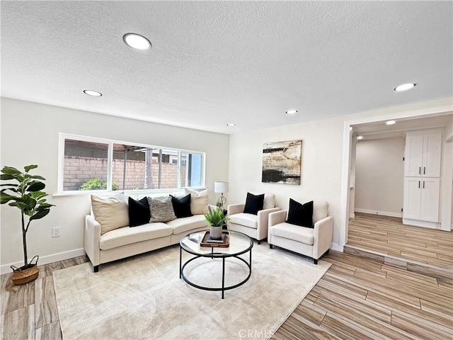 living area featuring recessed lighting, light wood finished floors, and a textured ceiling