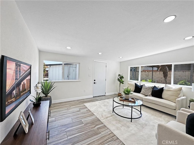 living area with recessed lighting, baseboards, wood finished floors, and a textured ceiling