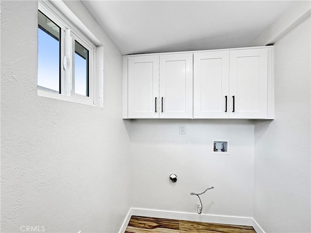 clothes washing area featuring washer hookup, hookup for a gas dryer, cabinet space, wood finished floors, and baseboards