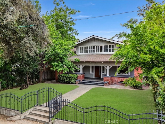 view of front of home featuring a gate, roof with shingles, a porch, a front lawn, and a fenced front yard