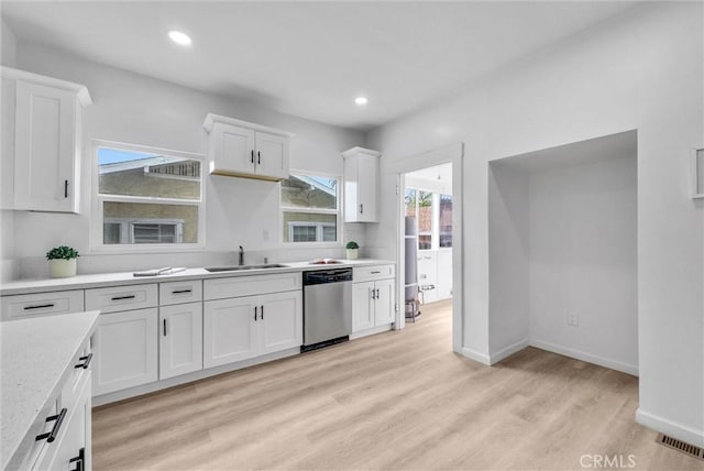 kitchen with white cabinets, light wood-style floors, dishwasher, and a sink
