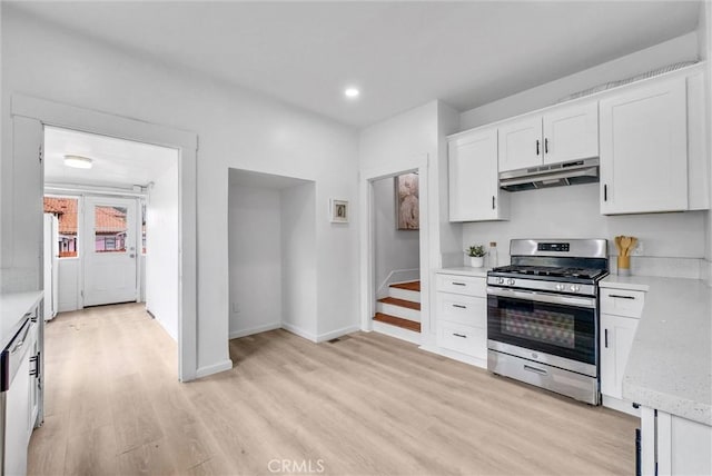 kitchen with baseboards, under cabinet range hood, light wood finished floors, gas stove, and white cabinetry