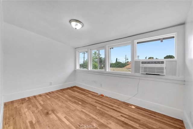 spare room featuring cooling unit, wood finished floors, and baseboards