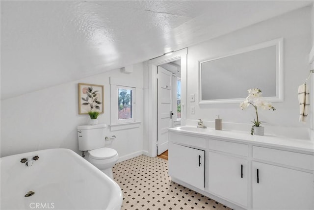 bathroom with a textured ceiling, a soaking tub, toilet, vaulted ceiling, and vanity