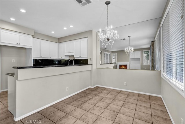 11 Santa Cruz Aisle, Irvine, CA 92606 - kitchen with a chandelier, under cabinet range hood, white cabinets, dark countertops, and visible vents