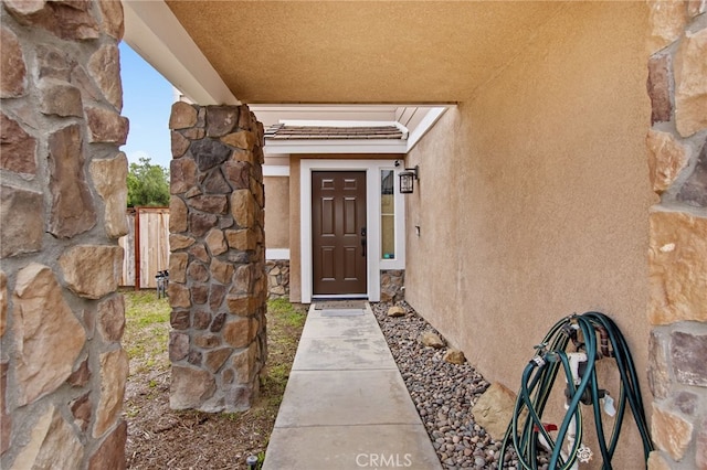 view of exterior entry featuring stone siding and stucco siding