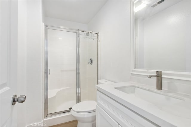 bathroom with visible vents, a shower stall, toilet, and vanity