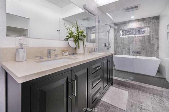bathroom with a freestanding bath, a tile shower, a sink, double vanity, and visible vents