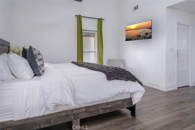 bedroom featuring baseboards, wood finished floors, and visible vents