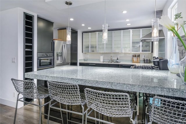 kitchen with oven, glass insert cabinets, recessed lighting, stainless steel fridge with ice dispenser, and a sink