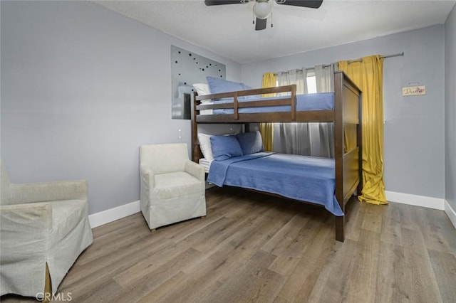 bedroom with a ceiling fan, baseboards, and wood finished floors