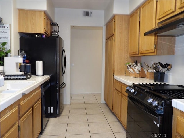 4012 Larkspur Ave, Rialto, CA 92377 - kitchen featuring visible vents, light tile patterned flooring, tile counters, under cabinet range hood, and black appliances