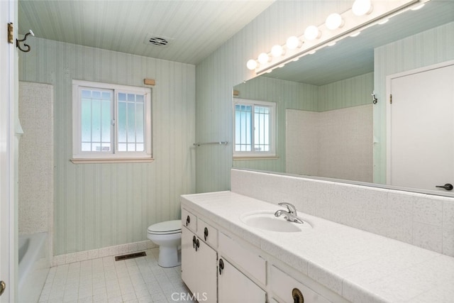 bathroom with toilet, baseboards, vanity, and wallpapered walls